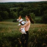 Woman holding corgi in her arms spinning in a meadow on McCormack Trail located in Hamilton, Ontario