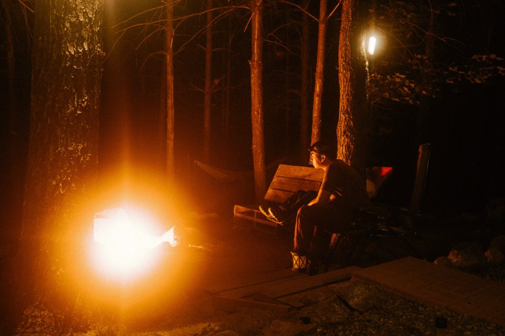 Man staring at the bonfire at Sibo's Bell Tent Glamping Site in Verona, Ontario
