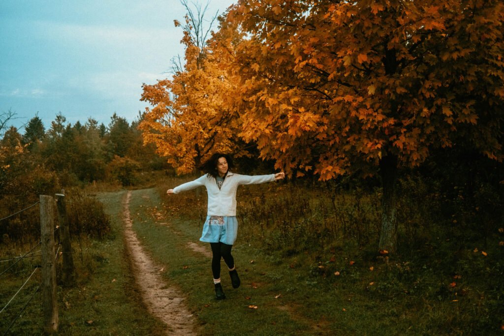 Woman in PJs twirling on the walking trails at Haute Goat during the autumn