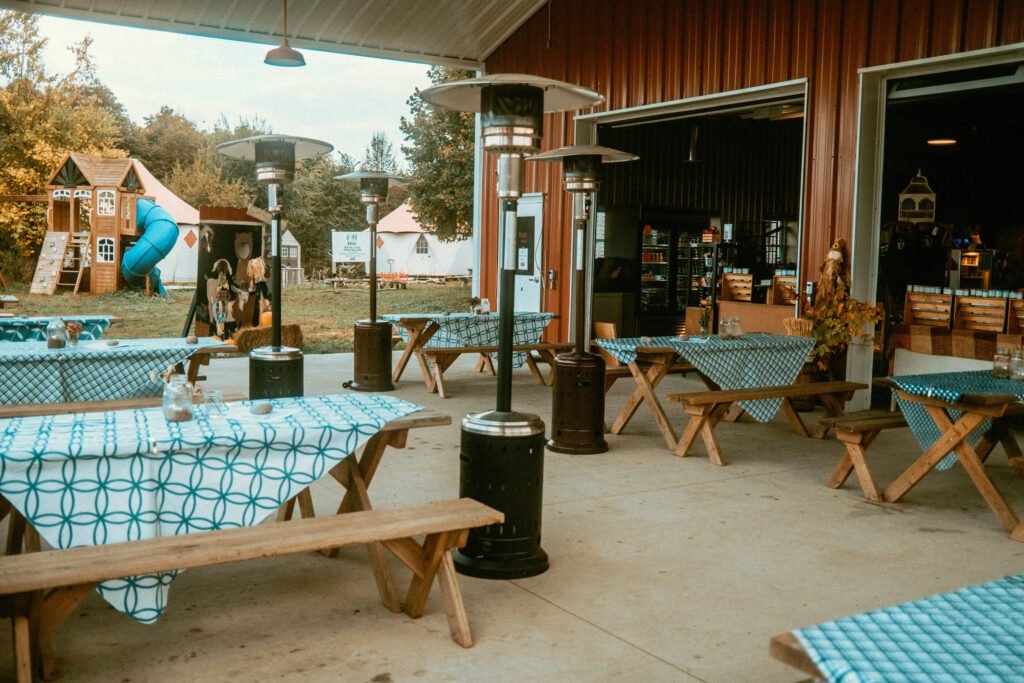 Detailed view of Screaming Goat Cafe's outdoor patio. Picnic benches have table clothes and are decorated with local plants, branches, fruits found around the farm.