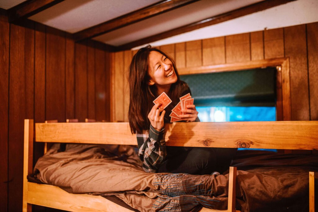 Maria from SYDE Road on the top bunk enjoying some card games in the rustic cozy cabin in Minden, Ontario - Hipcamp Canada Listing