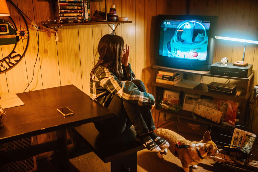 Maria from SYDE Road, watching Toy Story on a vintage CRT TV in the evening at the rustic cozy cabin in Minden, Ontario - Hipcamp Canada listing - 90s nostalgia