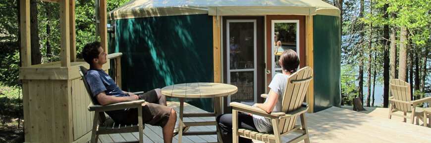 Couple sitting outside enjoying the sun in front of one of Bruce Peninsula National Park's yurts